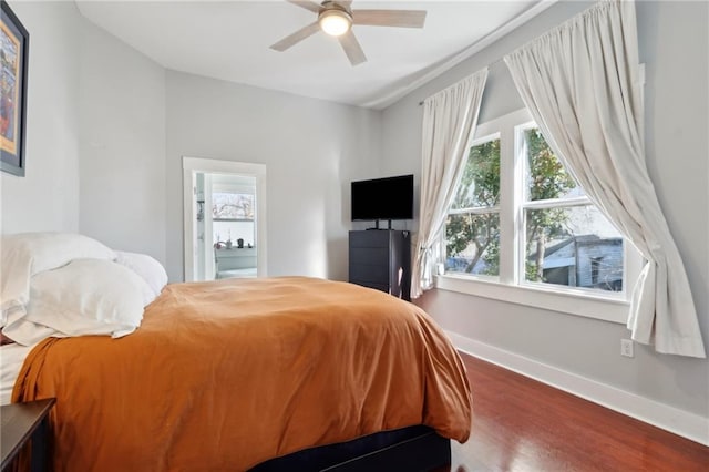 bedroom with a ceiling fan, baseboards, and wood finished floors