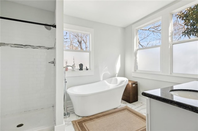 bathroom with a stall shower, a freestanding tub, and vanity