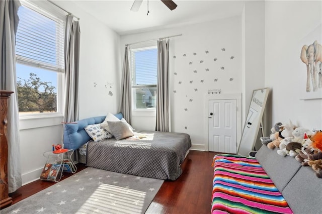 bedroom with multiple windows, baseboards, and wood finished floors