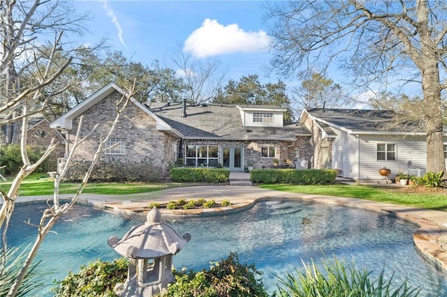 back of property featuring driveway, brick siding, and french doors