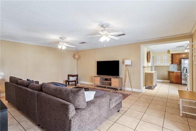 living area with visible vents, a ceiling fan, a textured ceiling, crown molding, and light tile patterned flooring