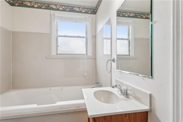 full bath featuring a tub to relax in, a wealth of natural light, and vanity