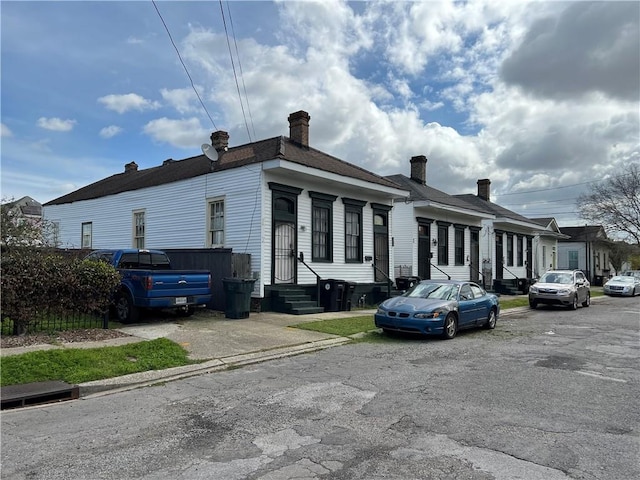 view of front of home with entry steps and a chimney