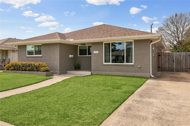 ranch-style house with roof with shingles, a front yard, a gate, and brick siding