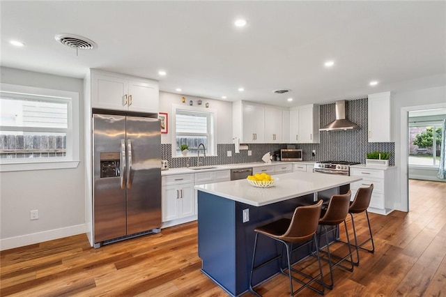 kitchen with wall chimney exhaust hood, visible vents, appliances with stainless steel finishes, and a wealth of natural light