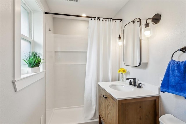 full bathroom featuring toilet, curtained shower, a wealth of natural light, and vanity