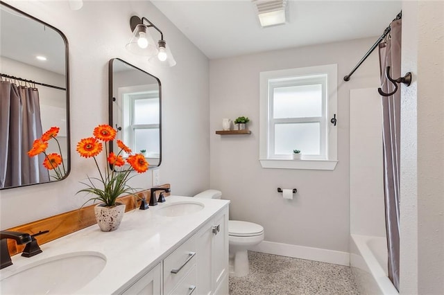 bathroom with speckled floor, a sink, and a healthy amount of sunlight