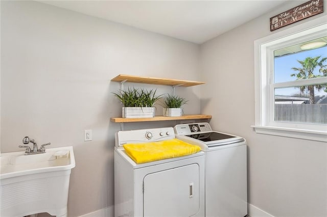 clothes washing area with laundry area, baseboards, separate washer and dryer, and a sink