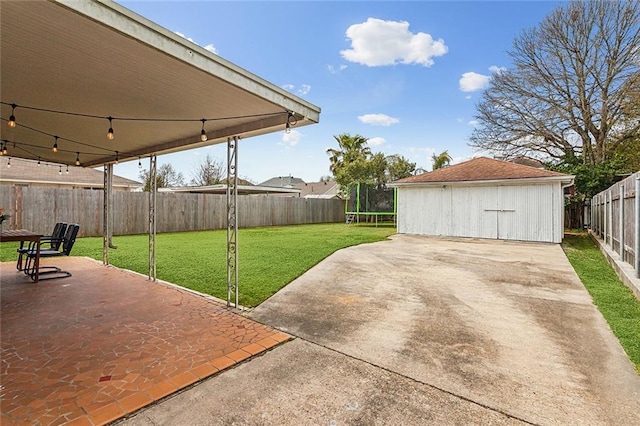 view of patio with a fenced backyard, a trampoline, a detached garage, and an outdoor structure