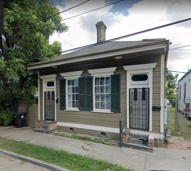 view of front of home featuring a chimney and fence