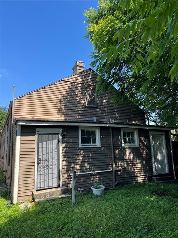 back of property featuring a lawn and a chimney