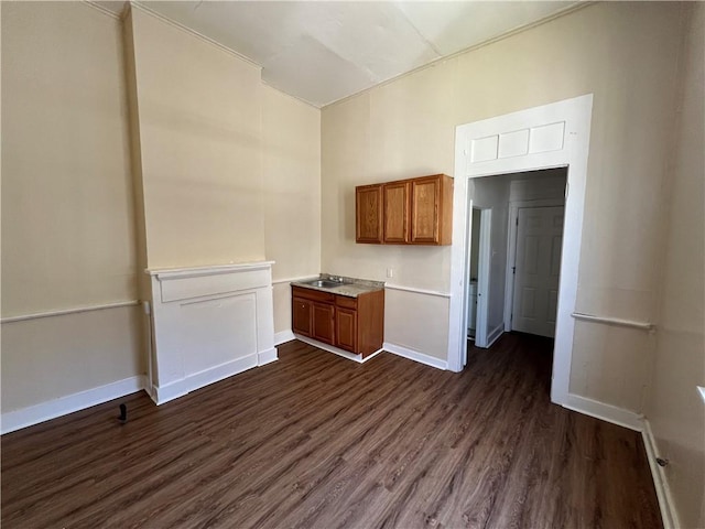 kitchen featuring baseboards, brown cabinets, dark wood-style flooring, and light countertops