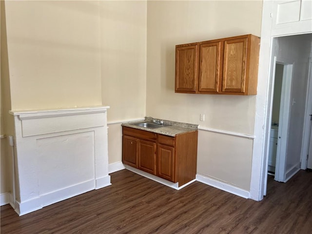 kitchen featuring dark wood-style floors, light countertops, brown cabinetry, and a sink