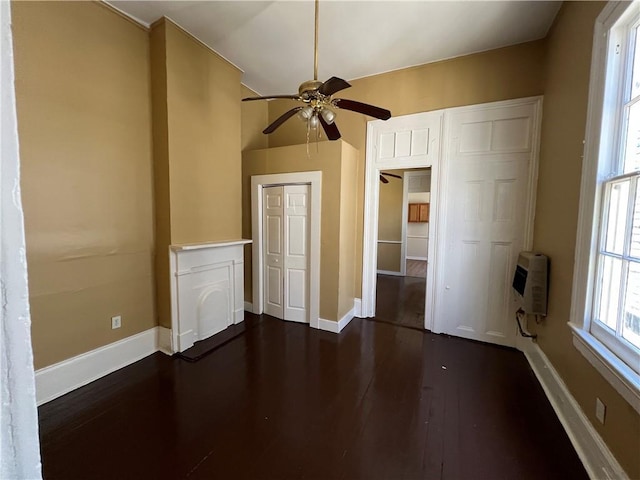 spare room with dark wood-type flooring, baseboards, heating unit, and a ceiling fan