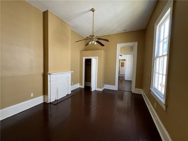 spare room featuring dark wood finished floors, a ceiling fan, and baseboards