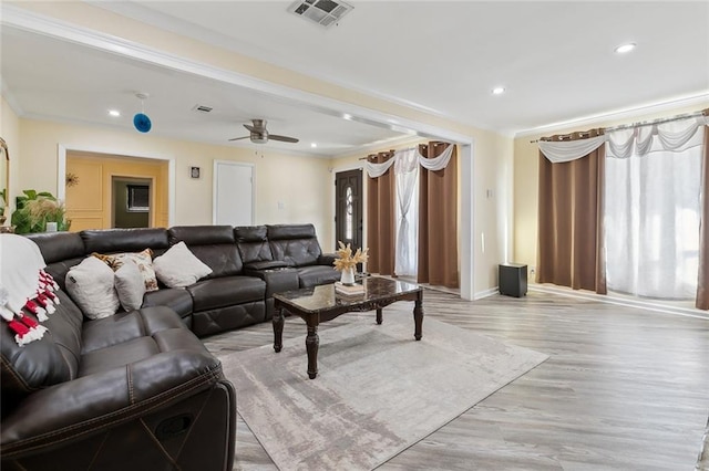 living area featuring light wood finished floors, plenty of natural light, visible vents, and crown molding