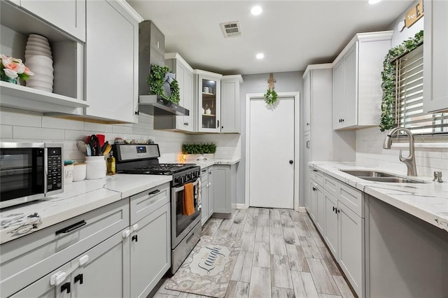 kitchen featuring appliances with stainless steel finishes, visible vents, a sink, and light stone counters