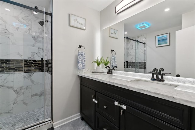 full bathroom featuring a sink, baseboards, marble finish floor, a marble finish shower, and double vanity