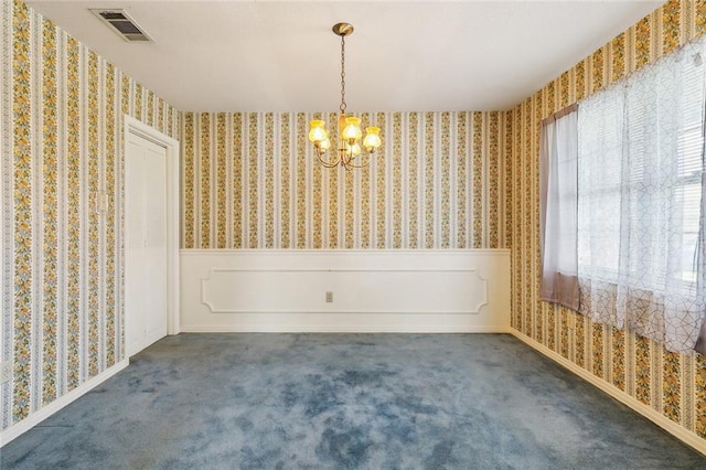 empty room featuring a wainscoted wall, carpet floors, visible vents, wallpapered walls, and an inviting chandelier