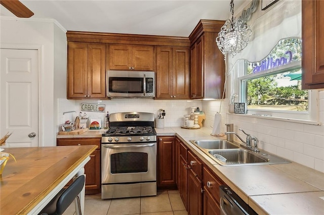 kitchen featuring light tile patterned floors, appliances with stainless steel finishes, backsplash, and a sink