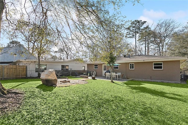 rear view of property featuring brick siding, a patio, a lawn, fence, and a fire pit