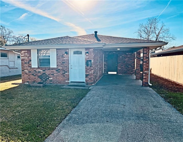 view of front of property with brick siding, fence, a front lawn, and roof with shingles