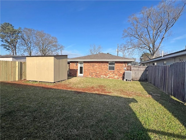 back of house with brick siding, a lawn, a shed, a fenced backyard, and an outdoor structure