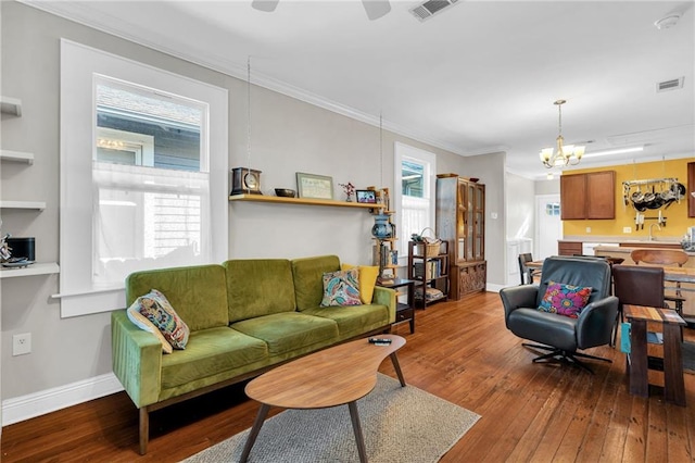 living area with baseboards, crown molding, visible vents, and hardwood / wood-style floors