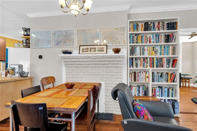 dining area with a notable chandelier, wood finished floors, and crown molding