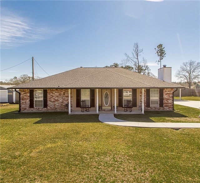 single story home featuring brick siding, a chimney, a front yard, and a shingled roof