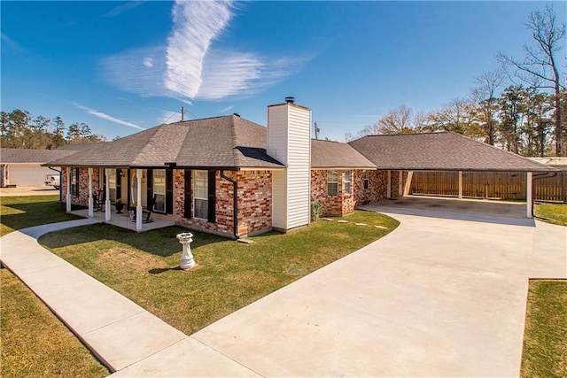 view of front facade with brick siding, a chimney, concrete driveway, fence, and a front lawn