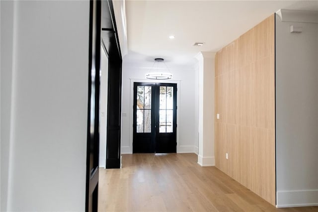 foyer entrance with light wood finished floors, baseboards, and french doors