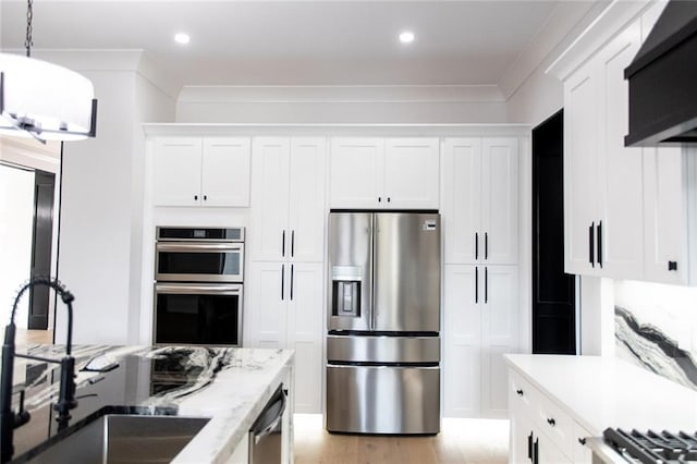 kitchen featuring pendant lighting, stainless steel appliances, a sink, and white cabinets