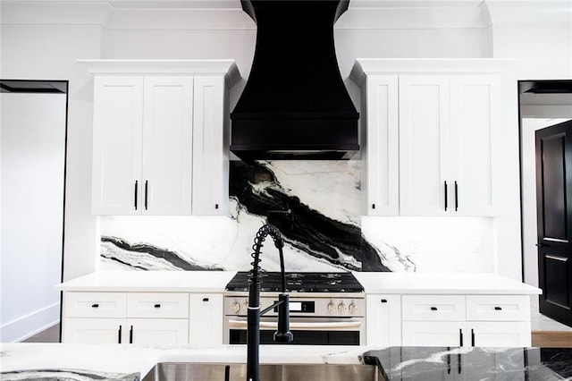 kitchen with stainless steel gas stove, tasteful backsplash, white cabinetry, and custom range hood