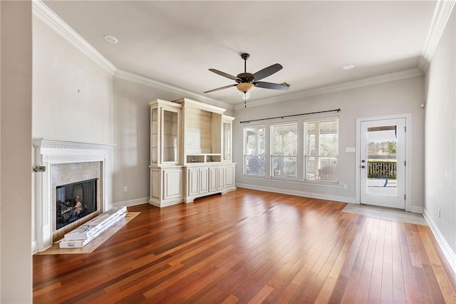 unfurnished living room with ceiling fan, a fireplace, baseboards, ornamental molding, and wood-type flooring