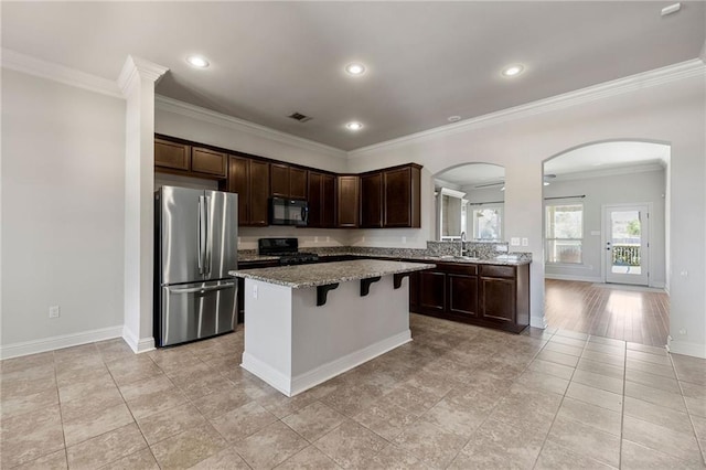 kitchen featuring visible vents, dark brown cabinets, a center island, black appliances, and a kitchen bar