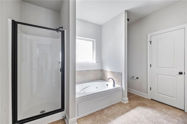 bathroom featuring baseboards, a shower stall, a tub with jets, and tile patterned floors