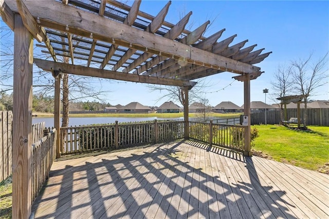 wooden terrace with a water view, fence, a pergola, and a lawn