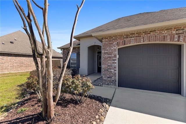 view of front of property featuring a garage, brick siding, driveway, and roof with shingles