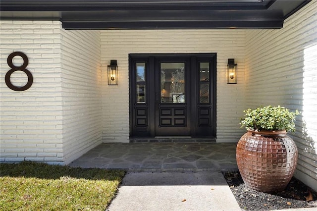 doorway to property featuring covered porch and brick siding