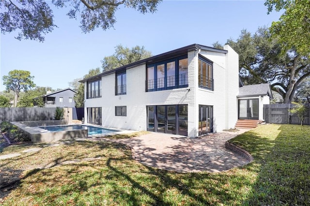 rear view of property featuring a fenced in pool, a lawn, a fenced backyard, french doors, and a patio area