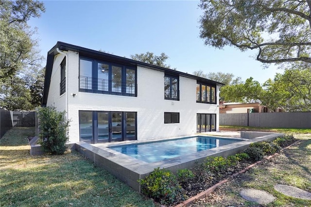 back of property featuring a fenced in pool, a fenced backyard, brick siding, and a lawn