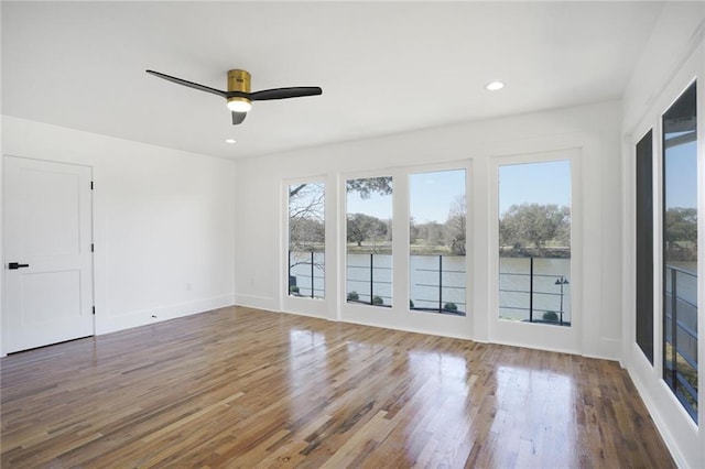 unfurnished room featuring baseboards, wood finished floors, a wealth of natural light, and recessed lighting