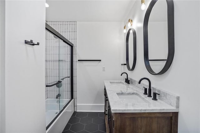 bathroom with baseboards, combined bath / shower with glass door, a sink, and tile patterned floors