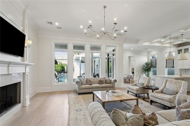 living area with light wood-style flooring, crown molding, a fireplace, a notable chandelier, and recessed lighting