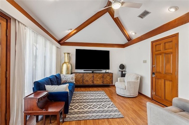 living area featuring vaulted ceiling with beams, visible vents, ceiling fan, wood finished floors, and baseboards