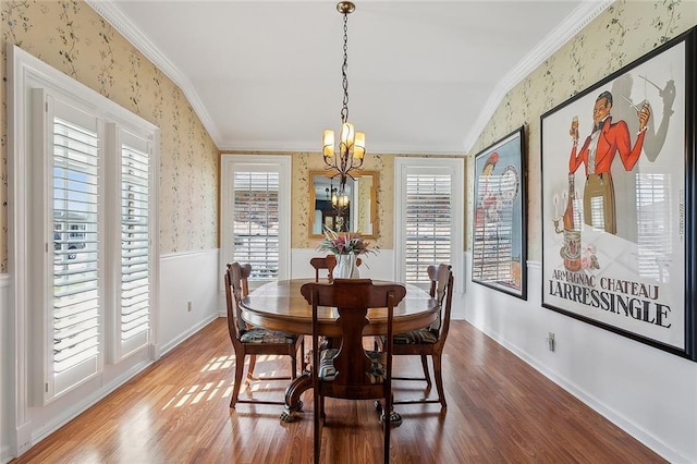 dining room featuring wallpapered walls, wood finished floors, crown molding, and wainscoting