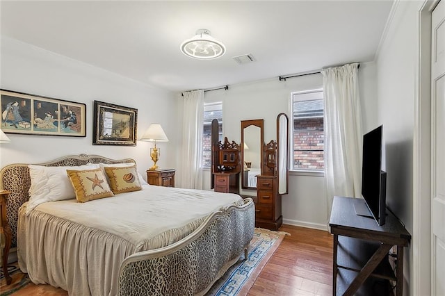 bedroom with wood finished floors, visible vents, baseboards, and multiple windows