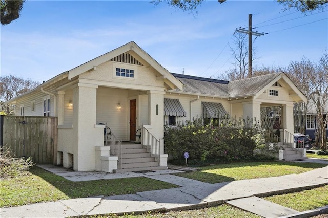 view of front of house featuring fence, a front lawn, and roof with shingles