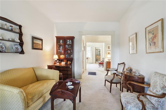 living area with ornamental molding and light colored carpet